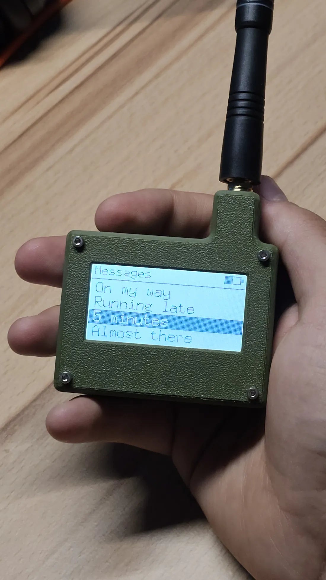 The D.C.S LoRa messenger in hand, showing a message on its lit screen